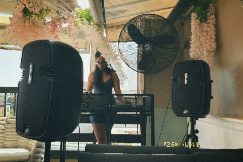 DJ Xhama playing a rooftop set surrounded by flowers